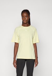 Lichtgele sportieve t-shirt met korte mouwen, voorzien van witte stiksels en een klein logo op de borst. Ontworpen voor comfort en bewegingsvrijheid.