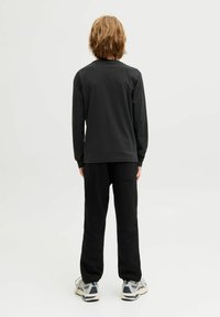 Fekete, hosszú ujjú póló és azonos színű melegítőnadrág puha anyagból, kényelmes fazonnal, látható hátsó zsebbel.