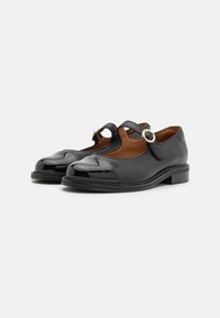 Zwarte leren Mary Jane-schoenen met gepolijste accenten op de tenen, ronde vorm, platte hak, verstelbare band met gouden ringdetail, gladde textuur.