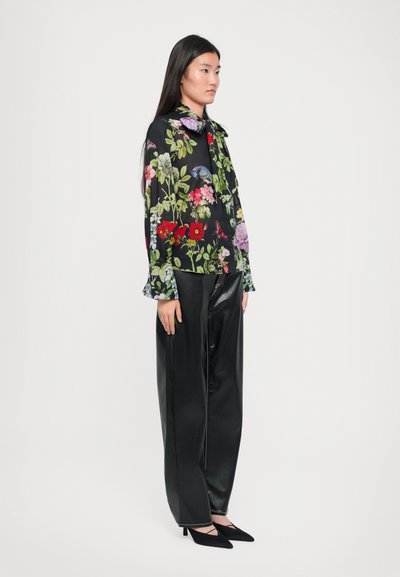 Black floral-patterned blouse with colorful flowers, ruffled cuffs, and a collar, paired with high-waisted black leather pants and pointed heels.