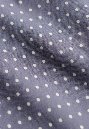 Blauwe stof met kleine witte stippen, toont textuur en lichte kreukels.