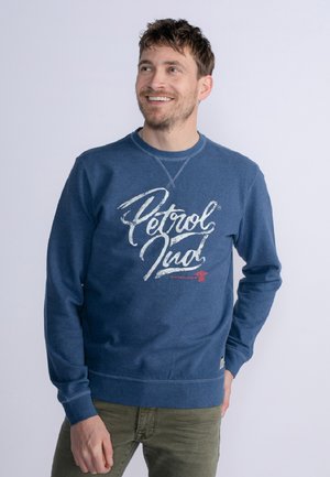 Niebieska bawełniana bluza z nadrukiem graficznym w białym i czerwonym kolorze. Okrągły dekolt oraz ściągacze na mankietach i u dołu. Gładka tekstura. Klasyczny krój.