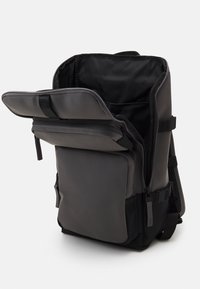 Grauer Rucksack mit strukturiertem Design, breiter Öffnung, Reißverschlussverschlüssen und einer Fronttasche. Hergestellt aus strapazierfähigen Materialien mit strukturierten Akzenten.