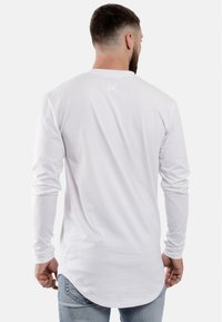 Witte longsleeve t-shirt van zachte katoen, met een ronde onderkant en een klein logo geborduurd op de bovenrug.