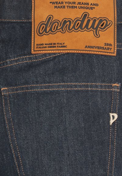 Mørkeblå denimjeans med en orange læderetiket, der står "dondup 25th ANNIVERSARY." Har kontrasterende orange syning og lomme detaljer.
