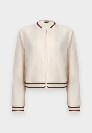 Veste zippée couleur crème avec poignets, col et ourlet côtelés à rayures marron et blanches, présentée sur un fond uni.