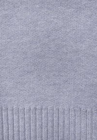 Svetlo modra pletenina z mehkimi teksturami. Ima rebrast spodnji rob, ki prikazuje enakomeren šiv in dosledn patterns čez celo. 