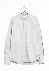 Světle šedá košile s dlouhým rukávem na knoflíky, která má límeček, kapsu na levé části hrudi a jemnou texturu látky s volným střihem.