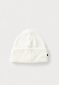 Căciulă albă din tricot cu nervuri, cu margine pliată și un mic logo brodat verde pe lateral, expusă întinsă pe un fundal alb.