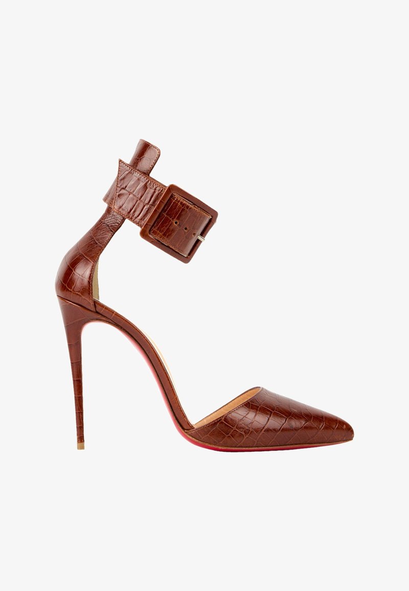 Chaussure marron à talon haut avec bout pointu, texture crocodile, bride à la cheville et grande boucle rectangulaire.