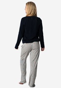 Haut à manches longues bleu marine et pantalon de pyjama gris clair avec des motifs festifs colorés, y compris des cœurs et des cannes en sucre. Tissu en coton doux et décontracté.