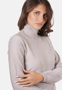 Maglione a collo alto grigio chiaro con collo a costine. Il tessuto lavorato presenta piccole scintille sparse per un'accento sottile.