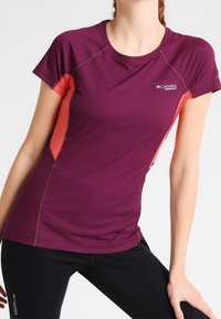 Kortärmad träningsskjorta i mörklila med korallfärgade accenter, som har en figurnära design och fuktavvisande tyg för aktiv användning.