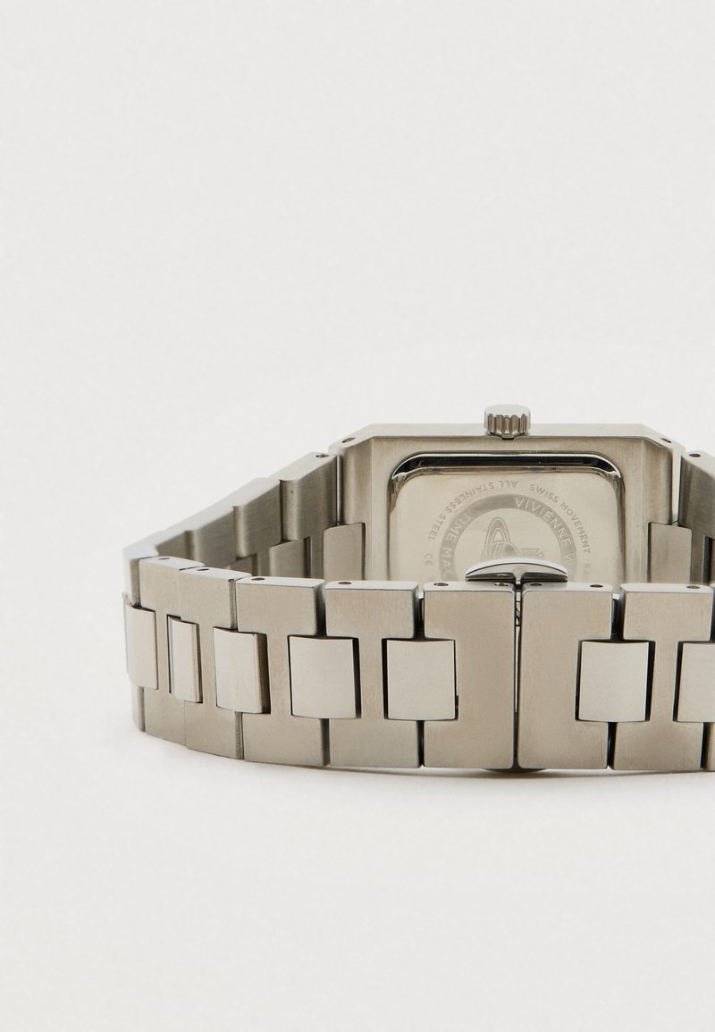 Metalen polshorloge met schakelband, rechthoekige kast achterzijde en sluiting, plat gelegd op een witte ondergrond.