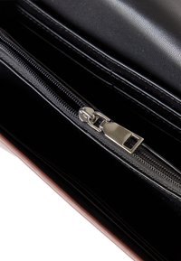 Interno di un portafoglio in pelle nera con una cerniera argentata, texture contrastante e fodera nera, con slot per carte e scomparti visibili.