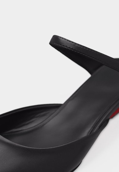 Μαύρο δερμάτινο παπούτσι slingback με μυτερή μύτη και κόκκινη σόλα, που δείχνει ομαλή υφή και λεπτομέρειες ραφής στο λουράκι.
