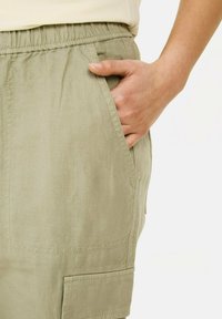 Lys grønne linnedshorts med elastisk talje, udstyret med sidelommer og en let struktureret overflade. Funktionelt og afslappet design.