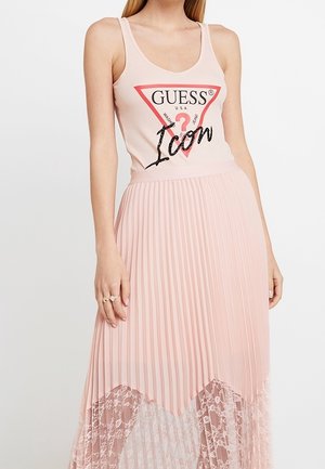 Vaaleanpunainen hihaton toppi, jossa mustin paljetein koristeltu "GUESS"-logo ja sana "Icon", yhdistetty pitkään, laskostettuun hameeseen, jossa on pitsireunus helmassa.