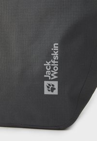 Sort stoffpose med en struktureret overflade prydet med sølvfarvet "Jack Wolfskin" logo og poteaftryk. Enkel, diskret design med afrundede hjørner.