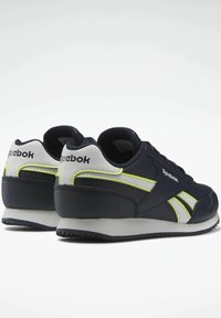 Marinblå sneakers med texturerad yta, med limegröna och vita detaljer, snörning och en vadderad ankelkrage för stöd.