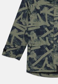 Manga de casaco verde com estampa abstrata de graffiti em azul escuro e detalhe de punho ajustável em Velcro.