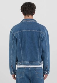 Denim jakna v srednje modri barvi s klasičnim krojem. Ima dva stranska žepa, gumbne zap closures in vidne niti. Mehka tekstura.