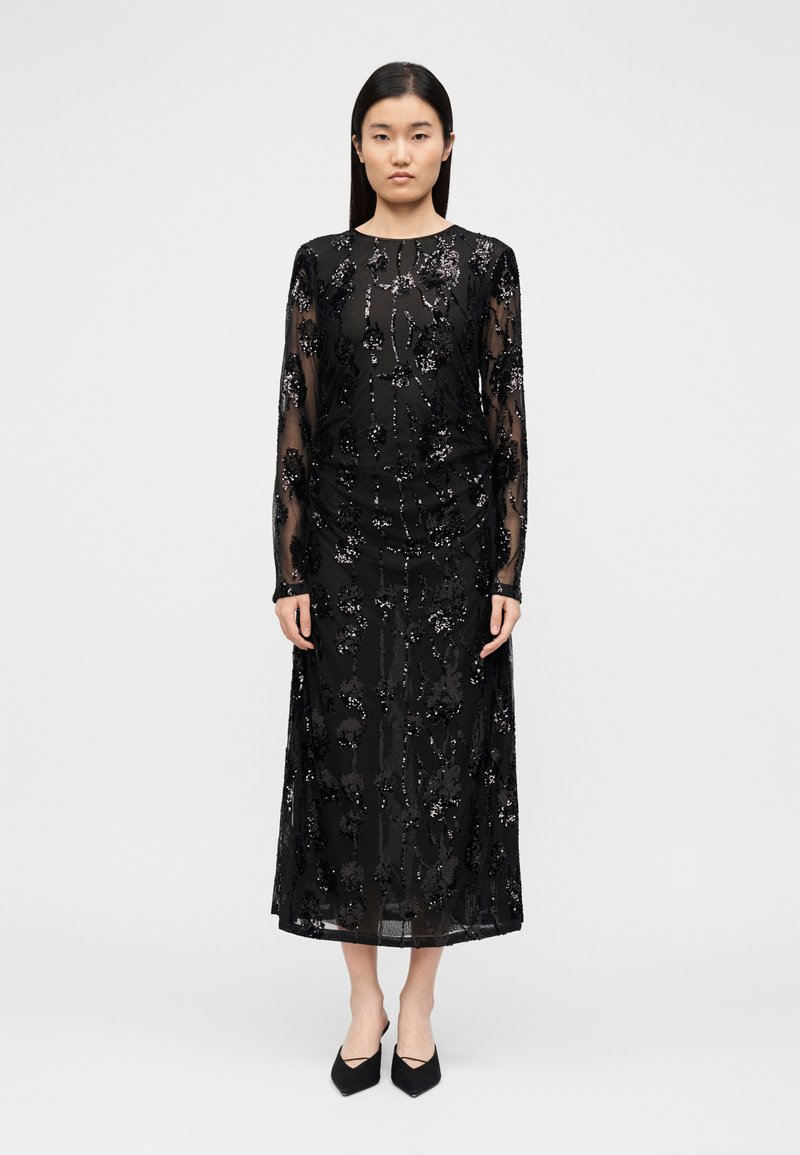 Must pikkade varrukatega kleit läbipaistva pealiskihiga, kaunistatud lillemotiividega litritega, sirge lõike ja pahkluu pikkuse servaga.