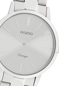 Silver Oozoo vintage wristwatch features a minimalist dial, metal strap, and understated hour markers with a polished finish.