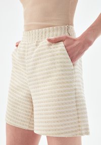 Béžové texturované šortky s horizontálním pruhovaným vzorem, bočními kapsami a pohodlným elastickým pasem.