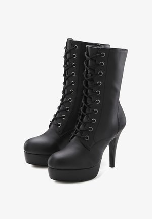 Black heeled ankle boots made of smooth synthetic material. Features include lace-up front with metal eyelets and a high stiletto heel.