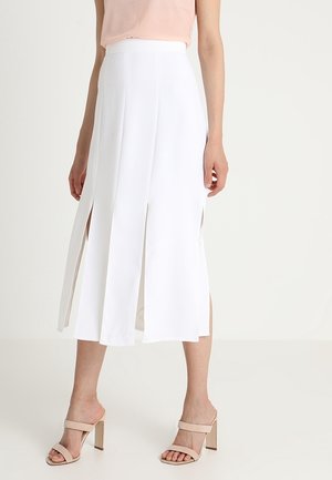 Hvid midi-nederdel med dobbelte sideslids, glat stof, høj talje-design, parret med beige blokhælsandaler.