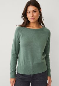 Maglione verde lavorato a maglia con scollo a barca, maniche lunghe, polsini a coste e orlo leggermente svasato. Tessuto morbido e vestibilità comoda.