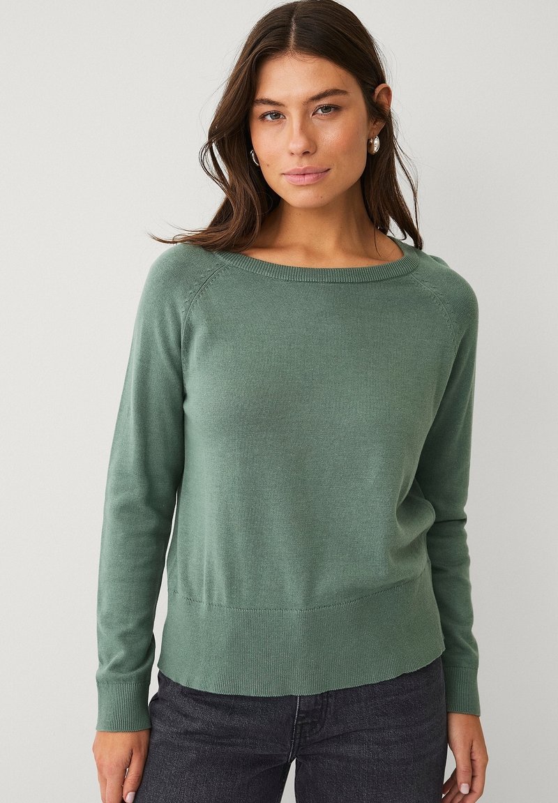 Maglione verde lavorato a maglia con scollo a barca, maniche lunghe, polsini a coste e orlo leggermente svasato. Tessuto morbido e vestibilità comoda.