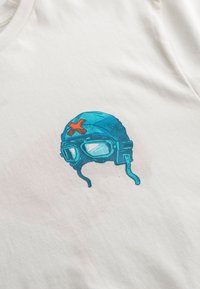 T-shirt bianco in cotone con grafica di un casco da aviatore vintage blu, occhiali e una stella rossa di accento. Tessuto liscio con taglio regolare.