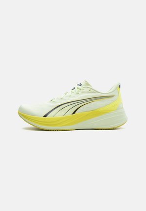 Pantof de alergare Puma de culoare verde deschis și galben, cu talpă groasă și dungi cu logo negru, prezentat din lateral pe un fundal alb.