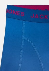 Blauwe onderbroek met een roze en blauwe elastische tailleband met de opschriften "JONES" en "JACK". Glad oppervlak met contrasterende stiksel details.
