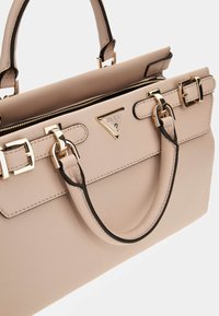 Beige nahkahandbag kultaisilla yksityiskohdilla, kolmiomaisella logolla, kaksinkertaisilla yläkäsittelyillä ja vetoketjulla. Ominaisuuksiin kuuluu jämäkkä muotoilun ja tasainen pohja.