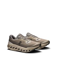 Lichte hardloopschoenen met een beige en grijze mesh bovenzijde, gevoerde zool met uitsparingen en zwarte accenten op de teen en het logo.