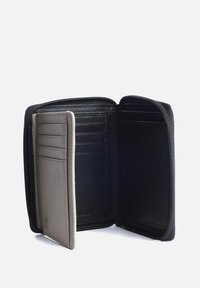 Schwarze Lederbörse mit einem Reißverschluss, auf einer Seite mit mehreren Kartenfächern aus grauem Leder und auf der anderen Seite mit einem glatten schwarzen Innenfutter.