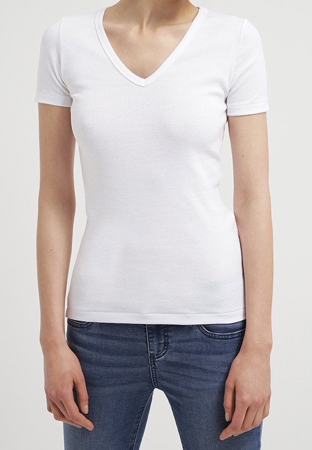 Vit kortärmad V-ringad t-shirt i blandad bomull med en figursydd design, kombinerad med blå denimjeans. Slät textur.