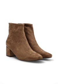 Botas de ante marrón hasta el tobillo con punta afilada y tacón bloque. Presentan una textura suave y lisa, y un diseño sencillo sin adornos.