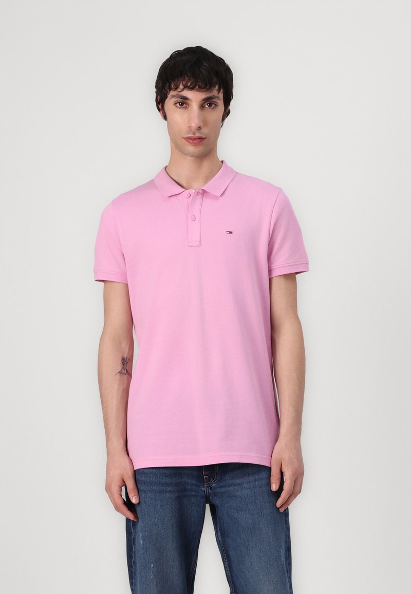 Rosa polo skjorta i bomull med en mjuk textur, med krage och en liten broderad logotyp på bröstet. Bärs med blå jeans.