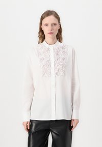 Chemise blanche à manches longues avec un panneau brod�é texturé rose clair à l'avant, dotée d'un col mandarin et d'une fermeture à boutons.
