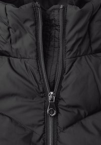 Giacca a vento nera con zip centrale evidente, hardware metallico, texture trapuntata e design con colletto alto.