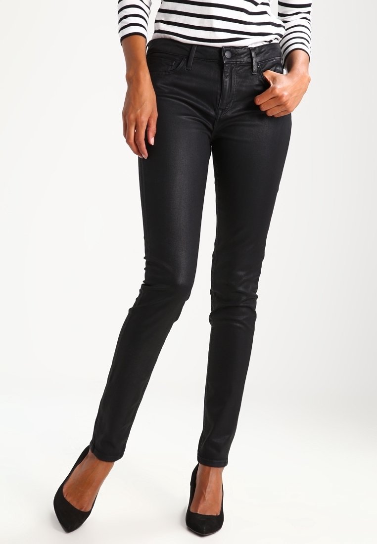 Svarta tajta jeans i ett mjukt, stretchigt material med framfickor, midja med bältesöglor och en subtil glans. Bärs med svarta klackar.