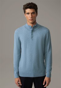 Pullover a maglia di un blu chiaro con colletto alto e pattina con bottoni. Presenta maniche lunghe e orlo a coste. Texture liscia.