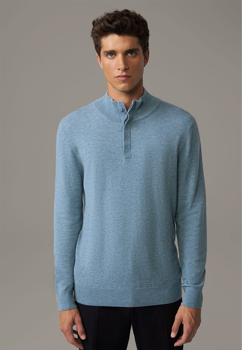 Pullover a maglia di un blu chiaro con colletto alto e pattina con bottoni. Presenta maniche lunghe e orlo a coste. Texture liscia.