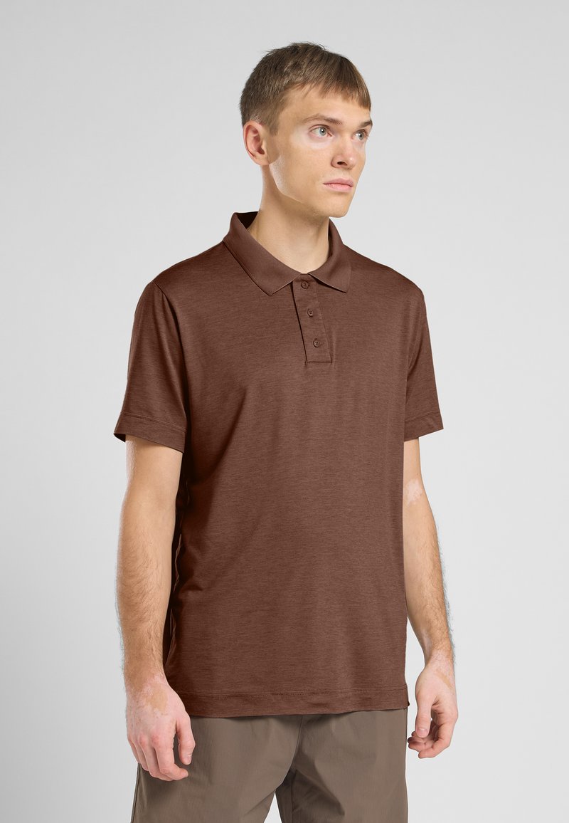 Polo marron à manches courtes, col classique, patte de boutonnage à trois boutons et tissu texturé. Porté avec un pantalon marron clair.