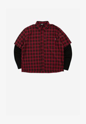 Piros és fekete kockás rövid ujjú ing fekete hosszú ujjú ing fölött, gallérral, begombolva és elöl zsebbel, fehér háttéren.