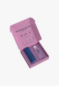 Blå sylinderformet sprayflaske og klar flaske i en rosa boks med informativ tekst. Begge flaskene har et elegant, moderne design.